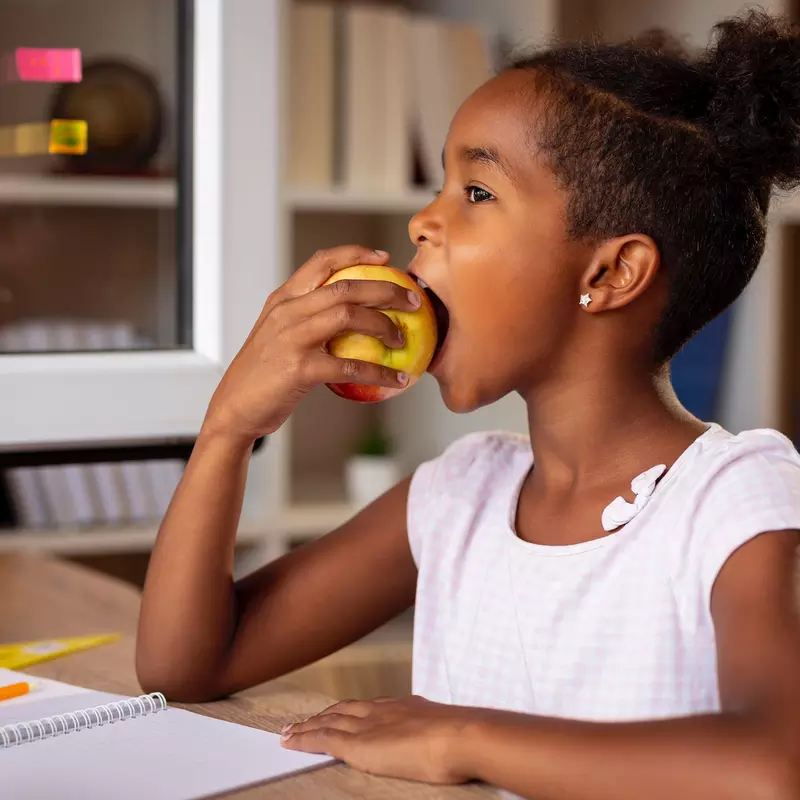 A little girl eats an apple for her healthy snack.