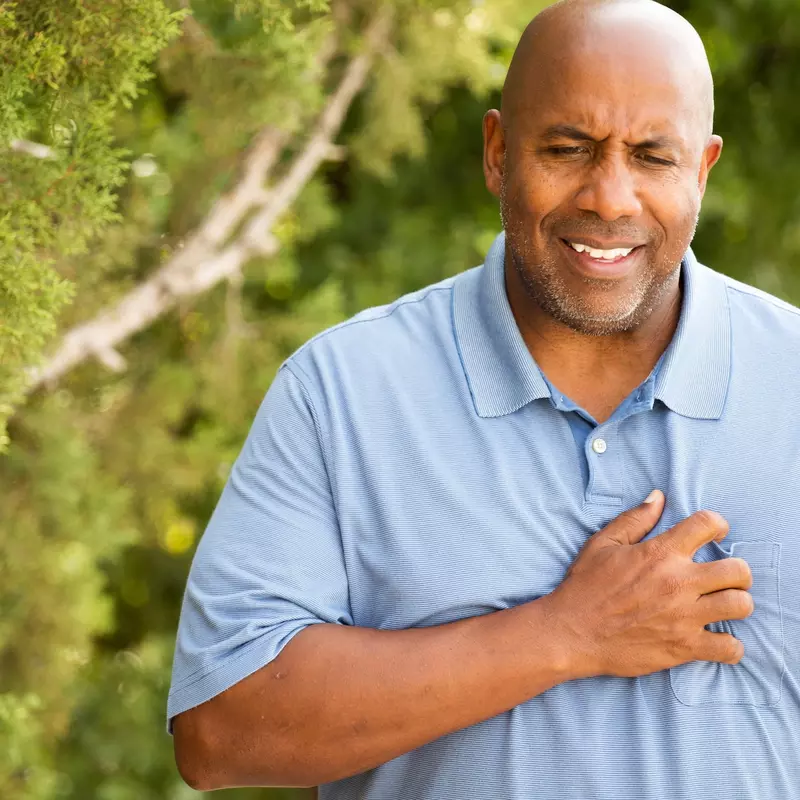 A man experiencing chest pain during a walk outdoors.