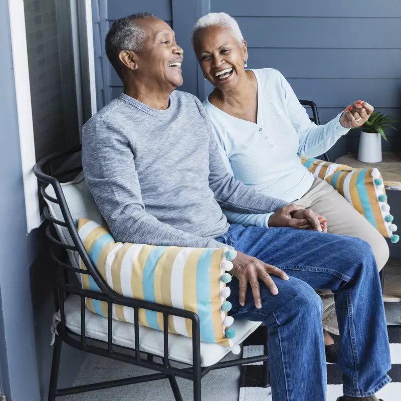 A couple laughing on their front porch together.