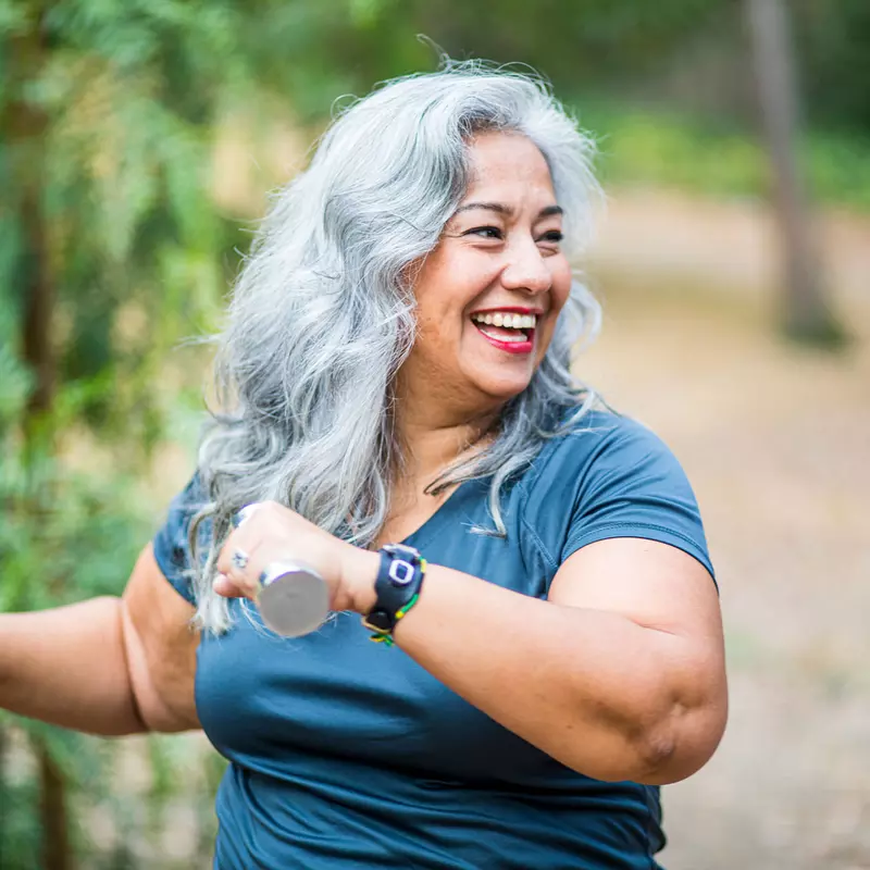 An overweight senior hispanic woman uses weights while she exercises