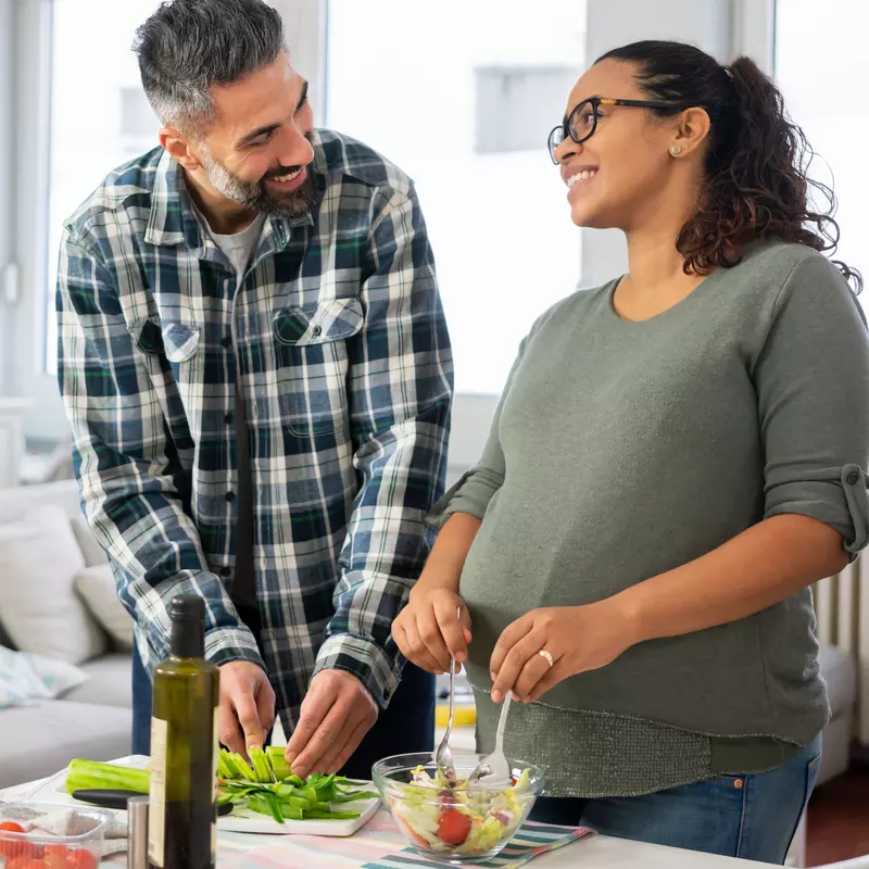A pregnant woman and her husband make a healthy meal.