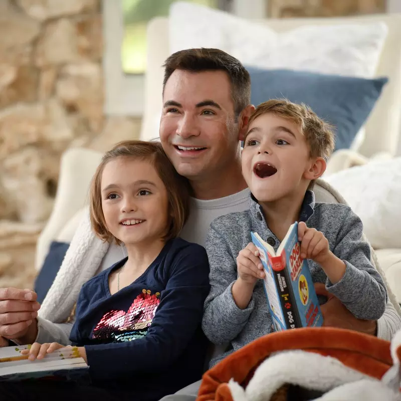 Father spending time with children reading books.