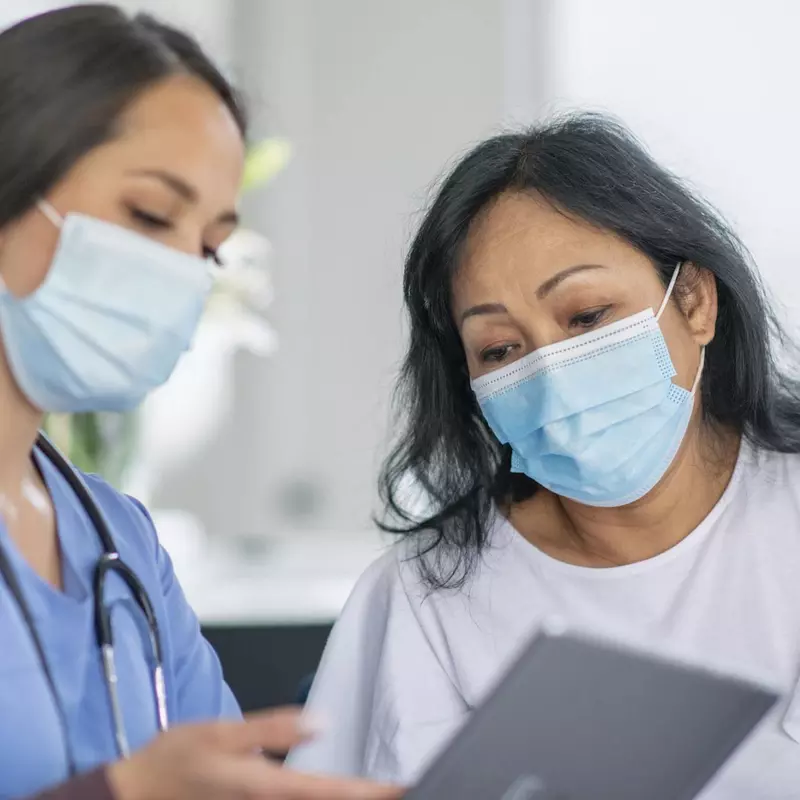 Doctor showing a patient how to schedule an appointment while wearing masks