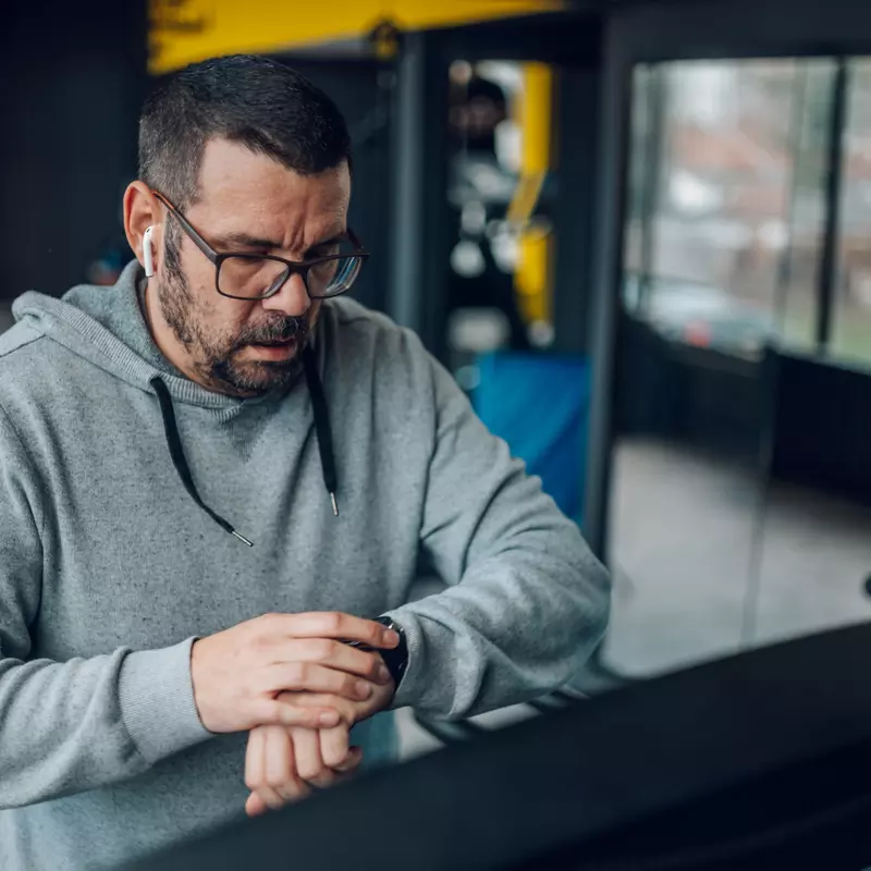 Man on a treadmill checking his watch