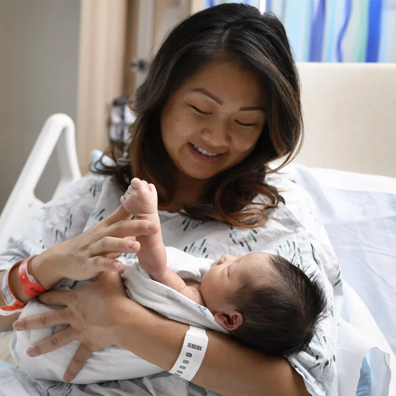 Mother holding her newborn baby in a hospital bed