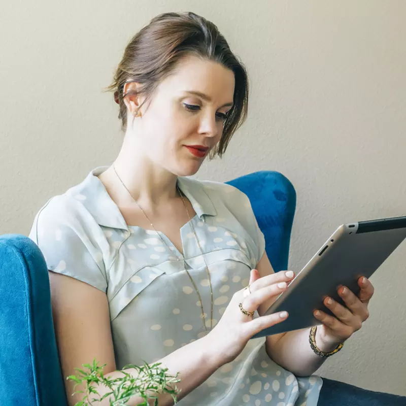 A young caucasian woman reads from her tablet indoors.