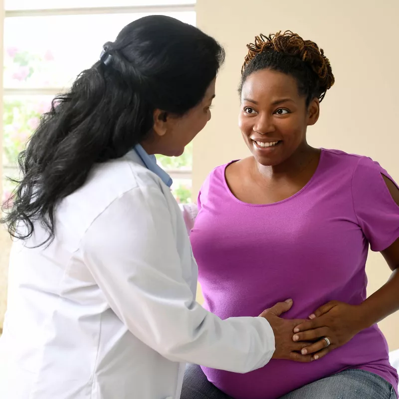 A nurse having a friendly conversation with a patient who is expecting a baby.