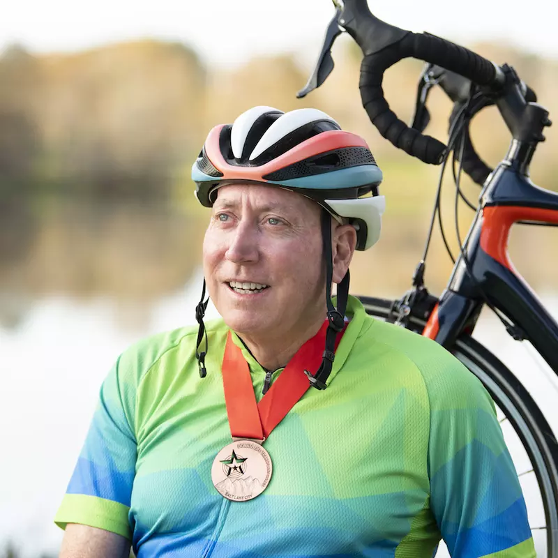 Man wearing a medal standing with his bike