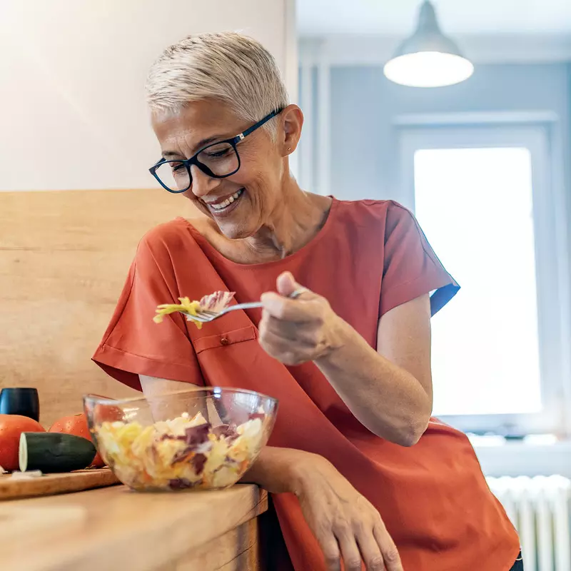 A woman eating a healthy salad at home.