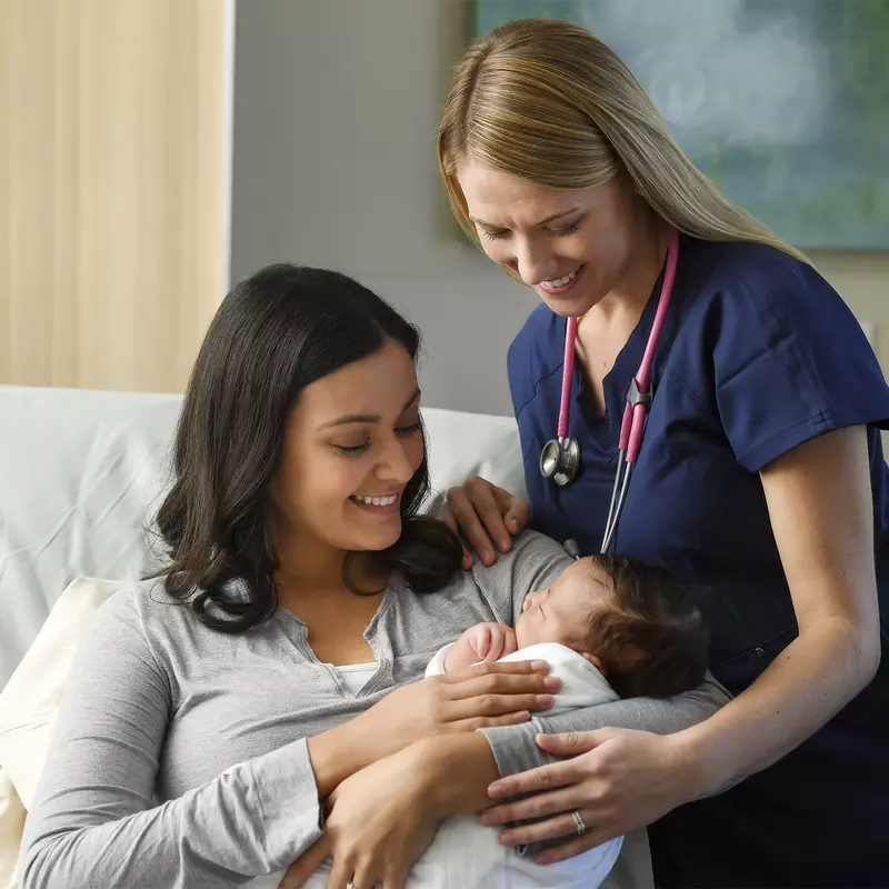 Mother and female physician holding baby 