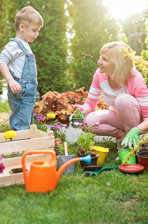 Grandmother and grandson gardening in a backyard.