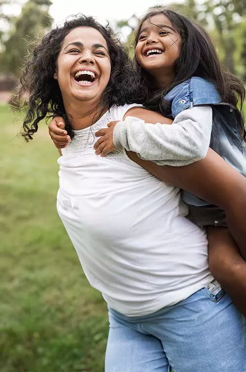 Mother with daughter on back outside