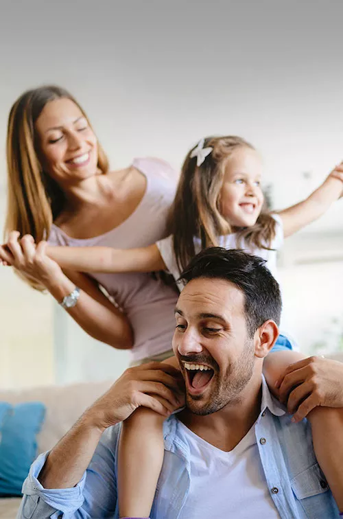 Man laughing carrying his daughter on his shoulders